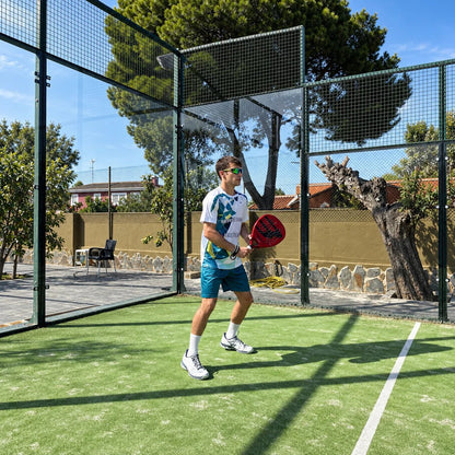 Jugador con equipación de pádel blanca y turquesa preparado para golpear en pista de césped
