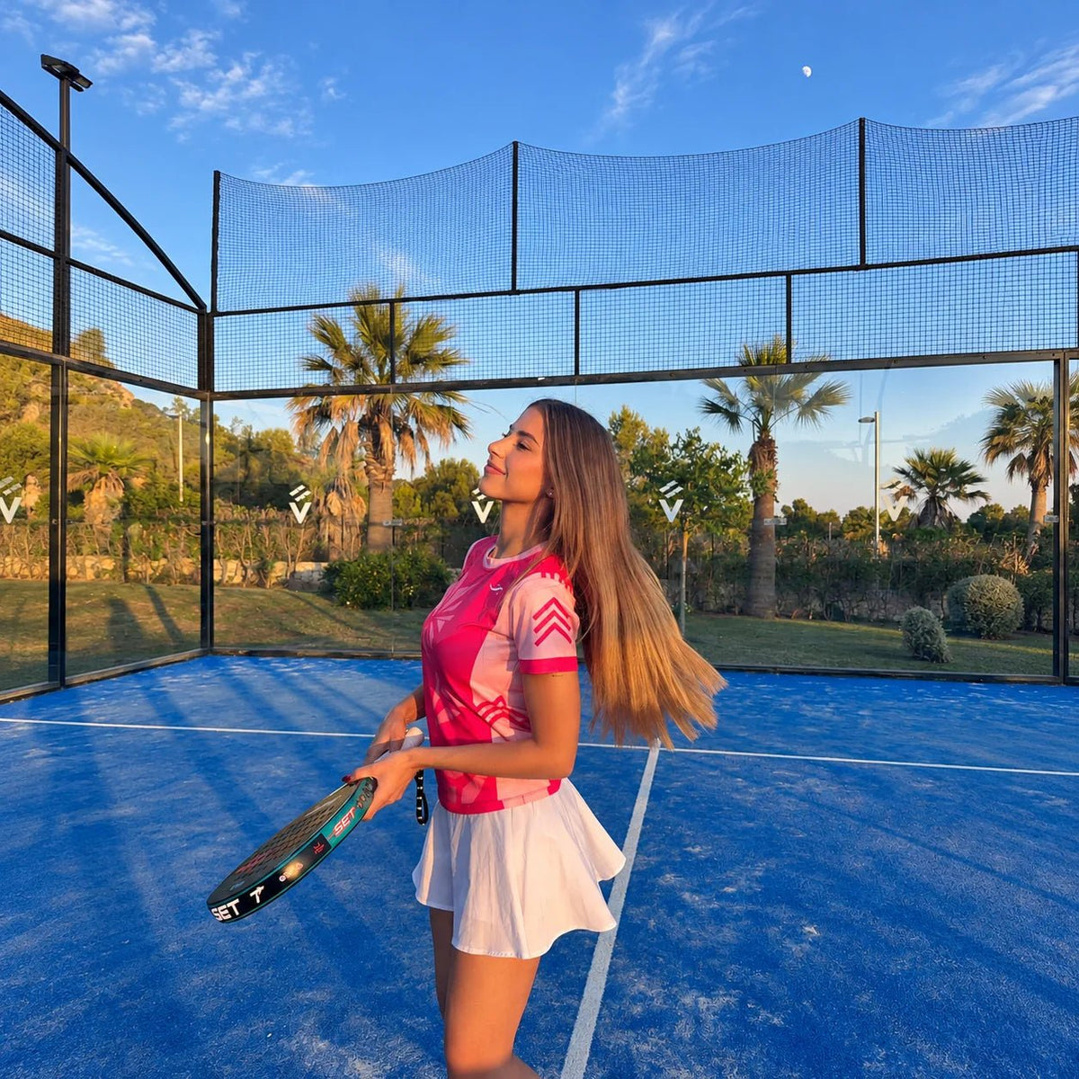 Jugadora con camiseta de pádel rosa fucsia sujetando la pala durante el juego